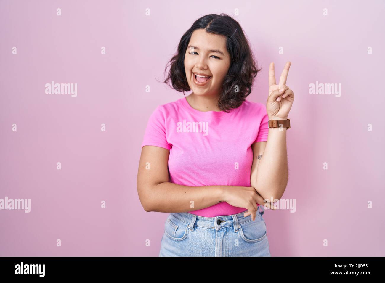 Young hispanic woman standing over pink background smiling with happy ...
