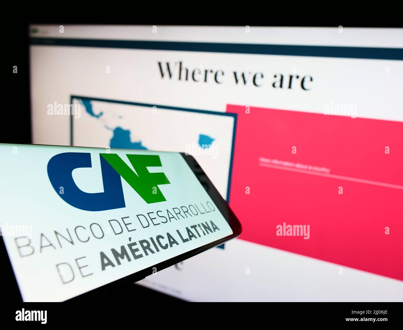 Cellphone with logo of Corporacion Andina de Fomento (CAF) on screen in front of business website. Focus on center-right of phone display. Stock Photo