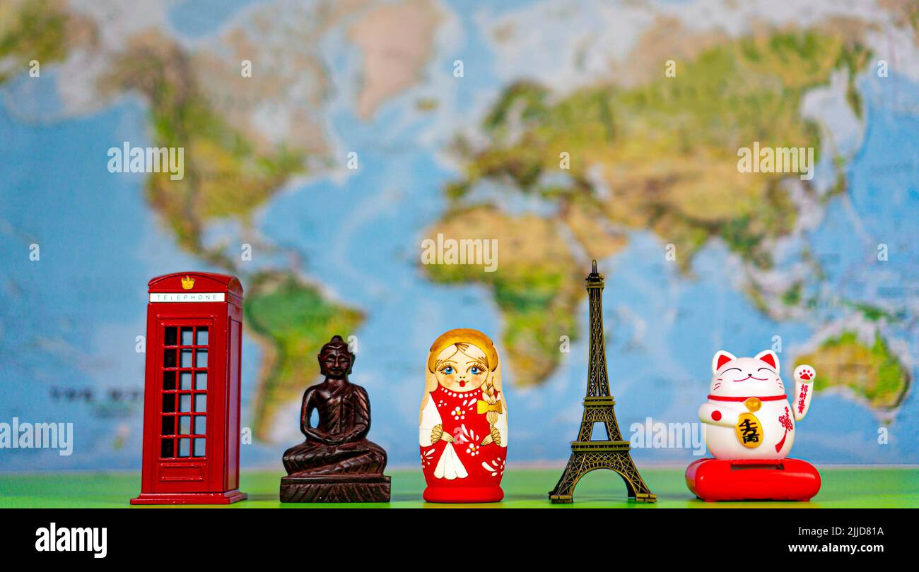 Souvenirs from around the world on the background of the world map. London red booth, statue of Buddha, russian doll Matryoshka, Eiffel tower, Maneki Stock Photo