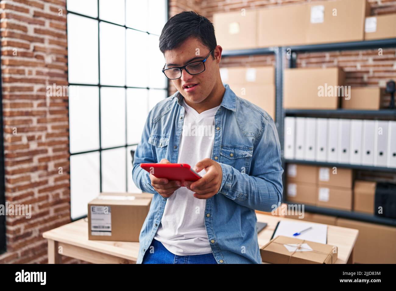 Down syndrome man ecommerce business worker using touchpad at office Stock Photo