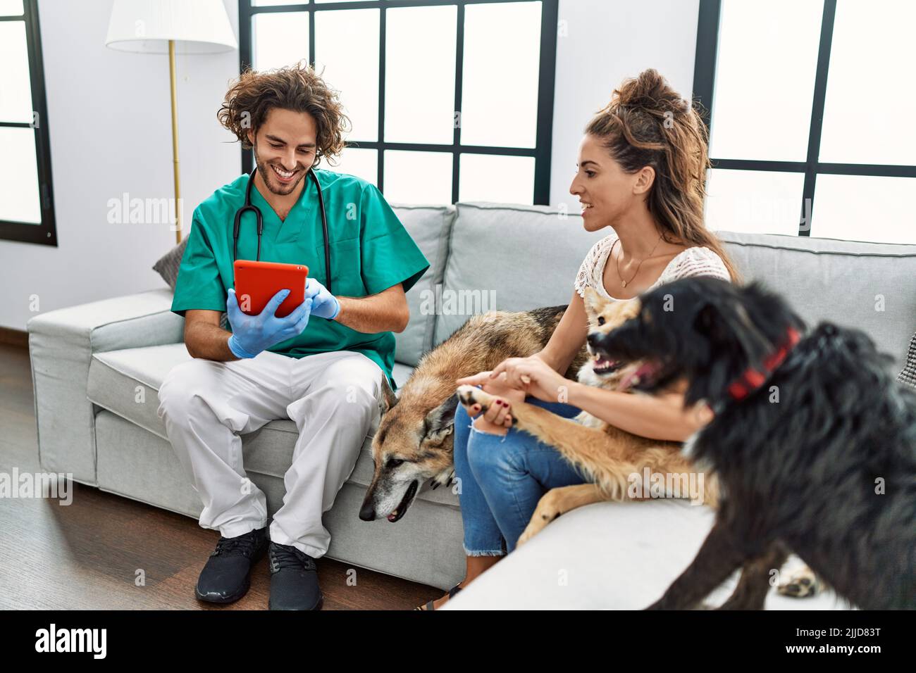 Man and woman wearing veterinarian uniform using touchpad at home Stock Photo Alamy