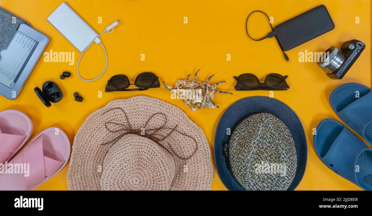Man and woman pair vacation accessories on the bright yellow background. Place for text or logo. Top view. Concept: family travel. Stock Photo