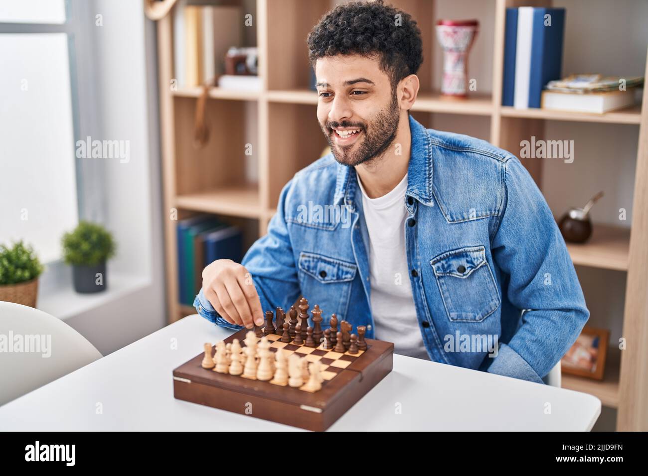 Young arab man playing chess sitting on table at home Stock Photo
