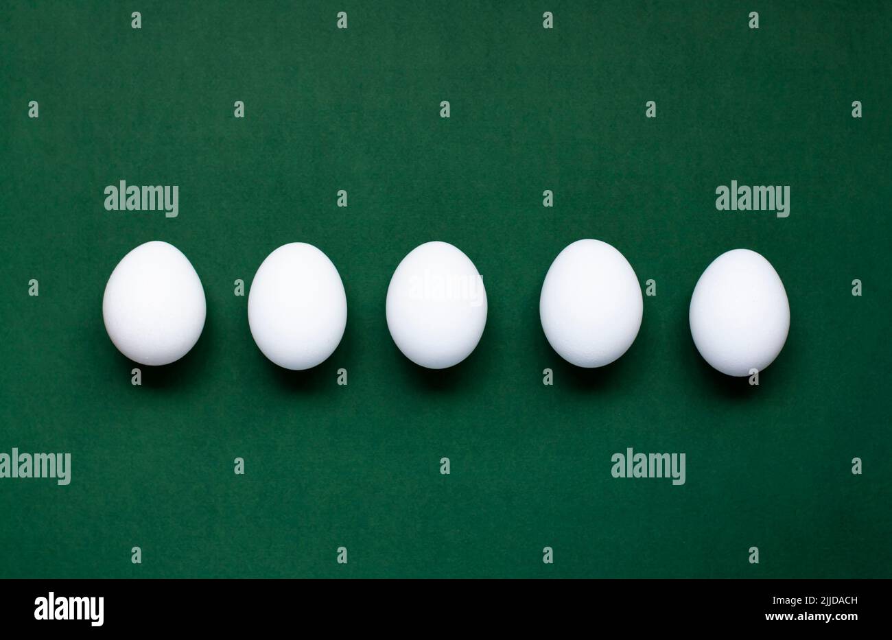 Five white eggs lie on a dark green background Stock Photo