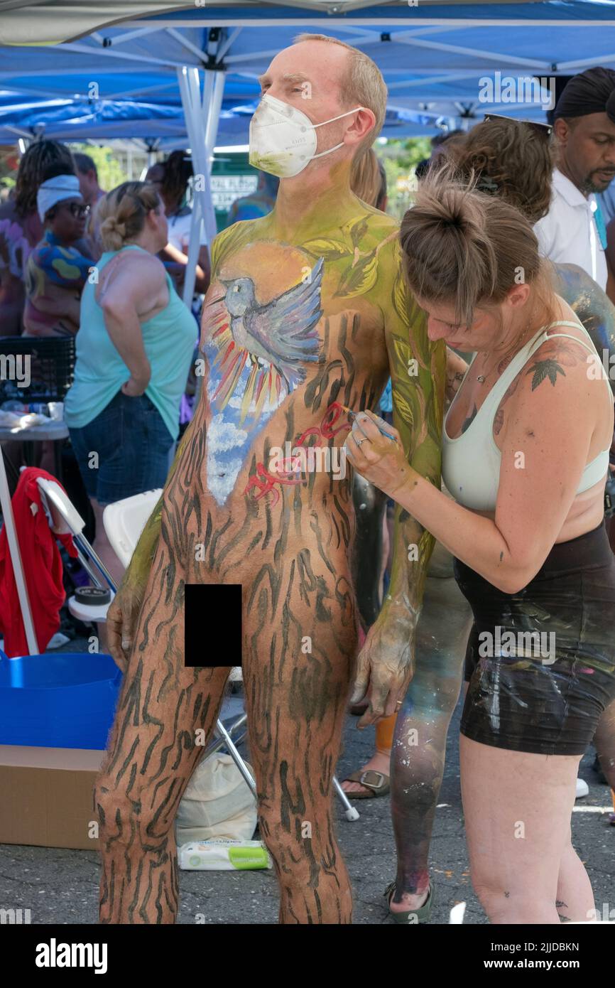 A middle aged man wearing a mask gets painted at NYC Body Painting Day in Union Square Park in Lower Manhattan, New York. Stock Photo