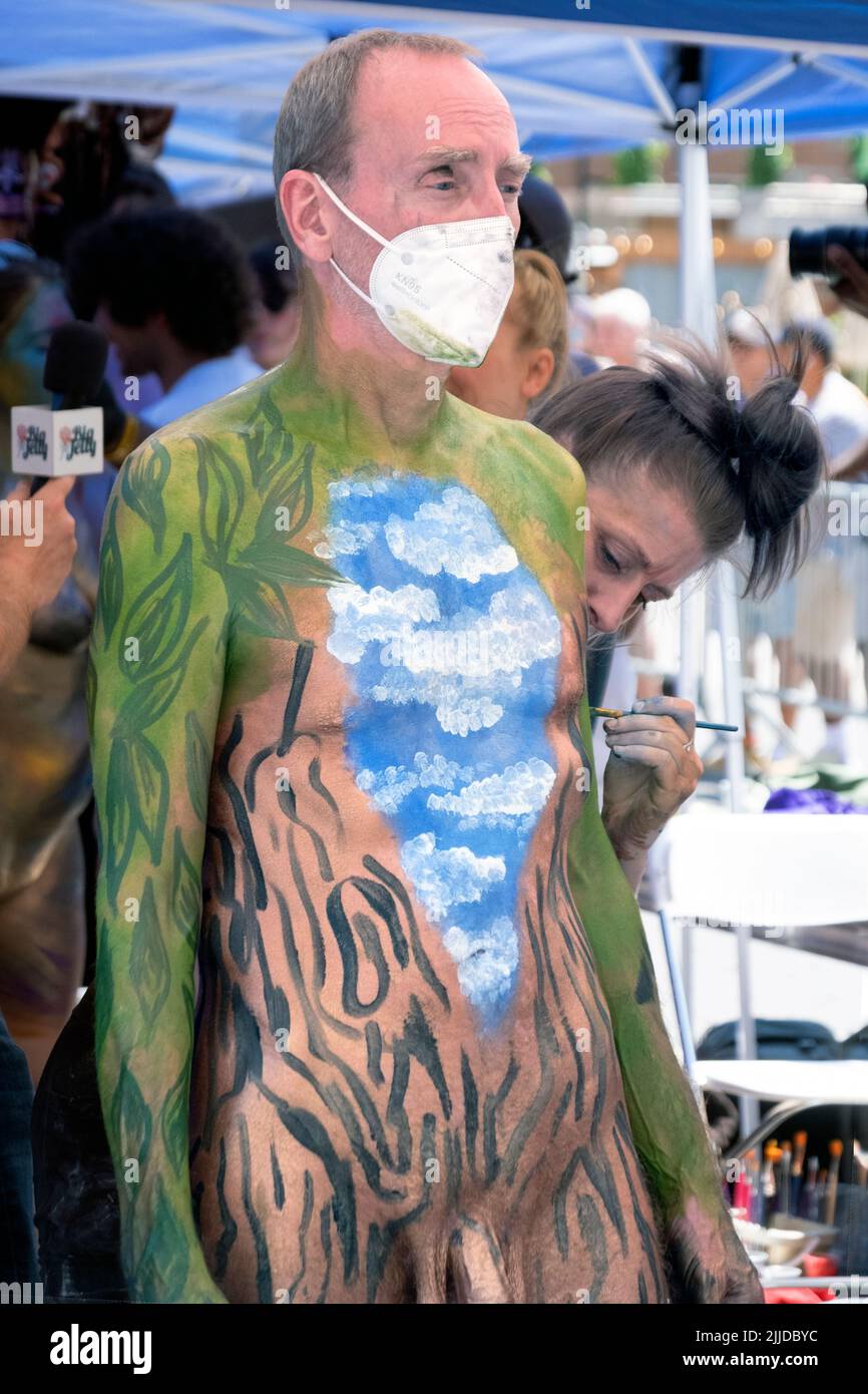 An older man wearing a mask gets painted at NYC Body Painting Day in Union Square Park in Lower Manhattan, New York. Stock Photo