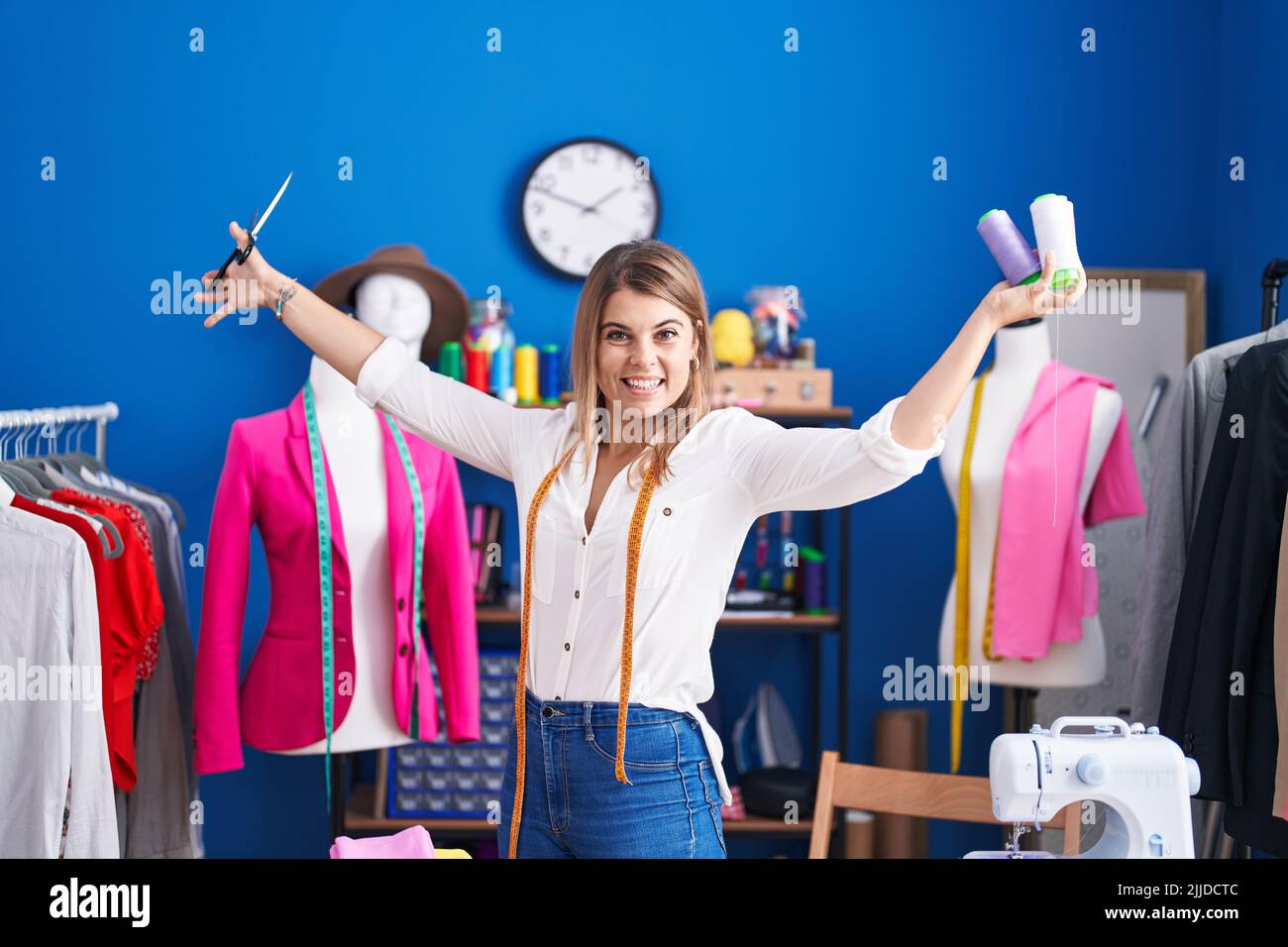 Young woman tailor smiling confident holding scissors and thread at ...