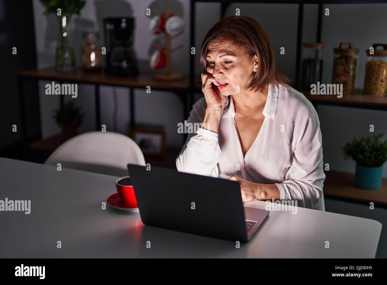 Middle age hispanic woman using laptop at home at night looking ...
