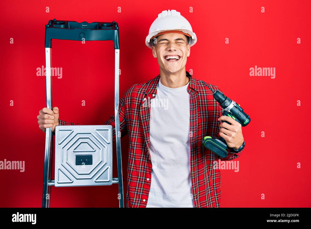 Young hispanic man holding screwdriver wearing hardhat by construction