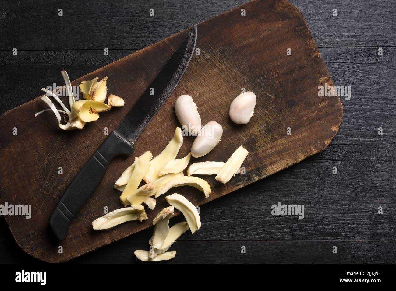 jackfruit flesh pieces and seeds on a cutting board, with a knife