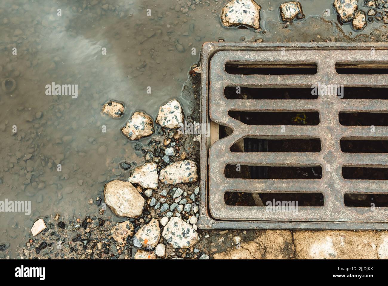 Water drains from the drain hatch. Drainage fountain of sewage. Accident in the sewage system. Dirty sewage flows on the road. Drainage system for was Stock Photo
