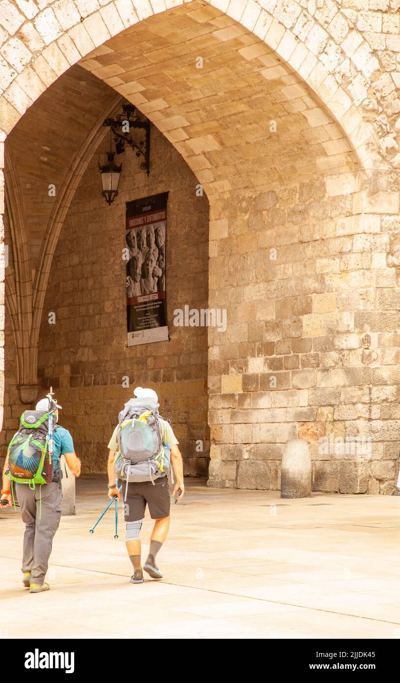 Pilgrims walking the Camino de Santiago, the way of St James entering the city gate of Santa ...