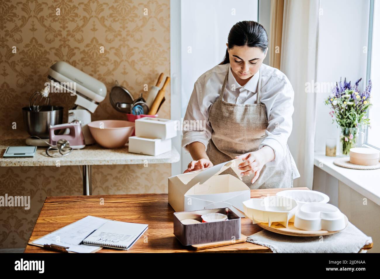 Female baker, pastry chef preparing cake order. Arabic Asian woman
