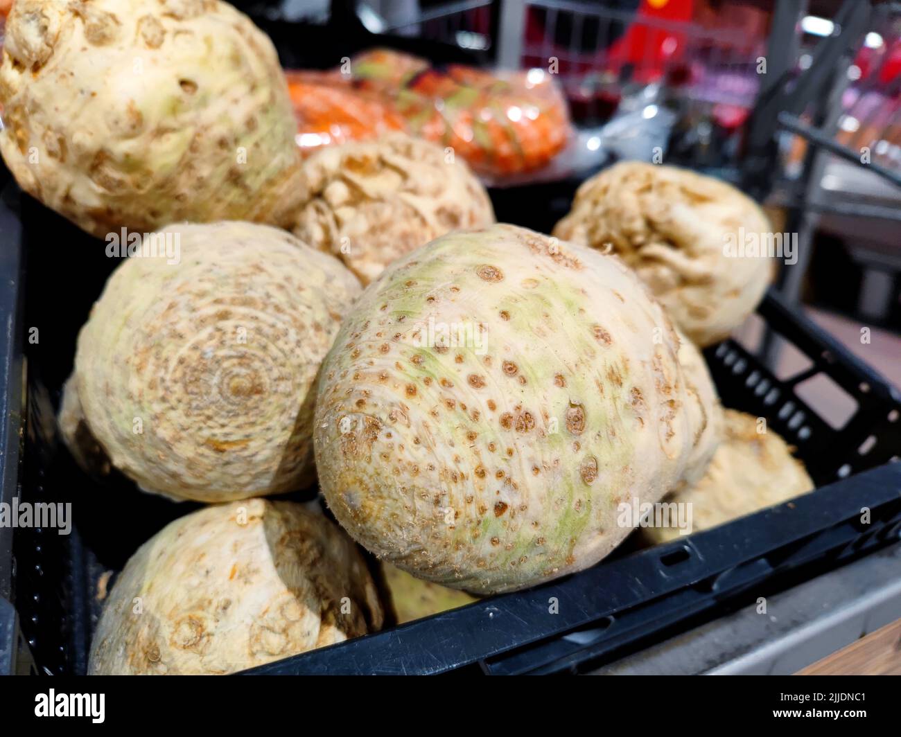 Unmarked celeriac are in a supermarket basket shelf ready to be sold Stock Photo