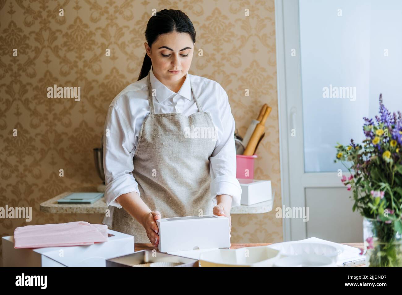 Female baker, pastry chef preparing cake order. Arabic Asian woman
