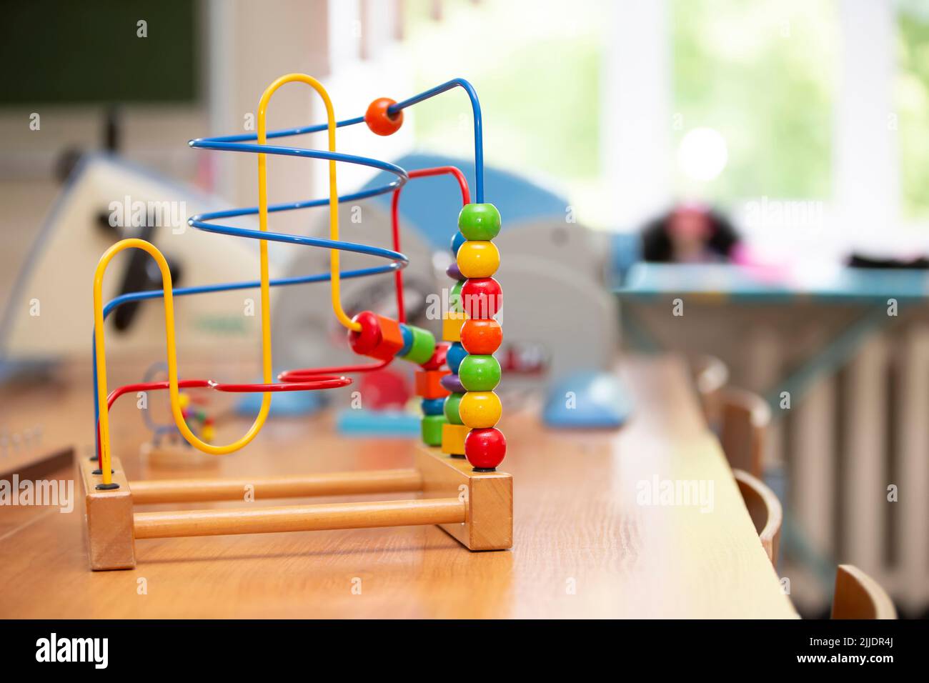 Children's toy labyrinth, maze on a metal spiral with ball, cylinder, cube on a wooden stand close-up Stock Photo