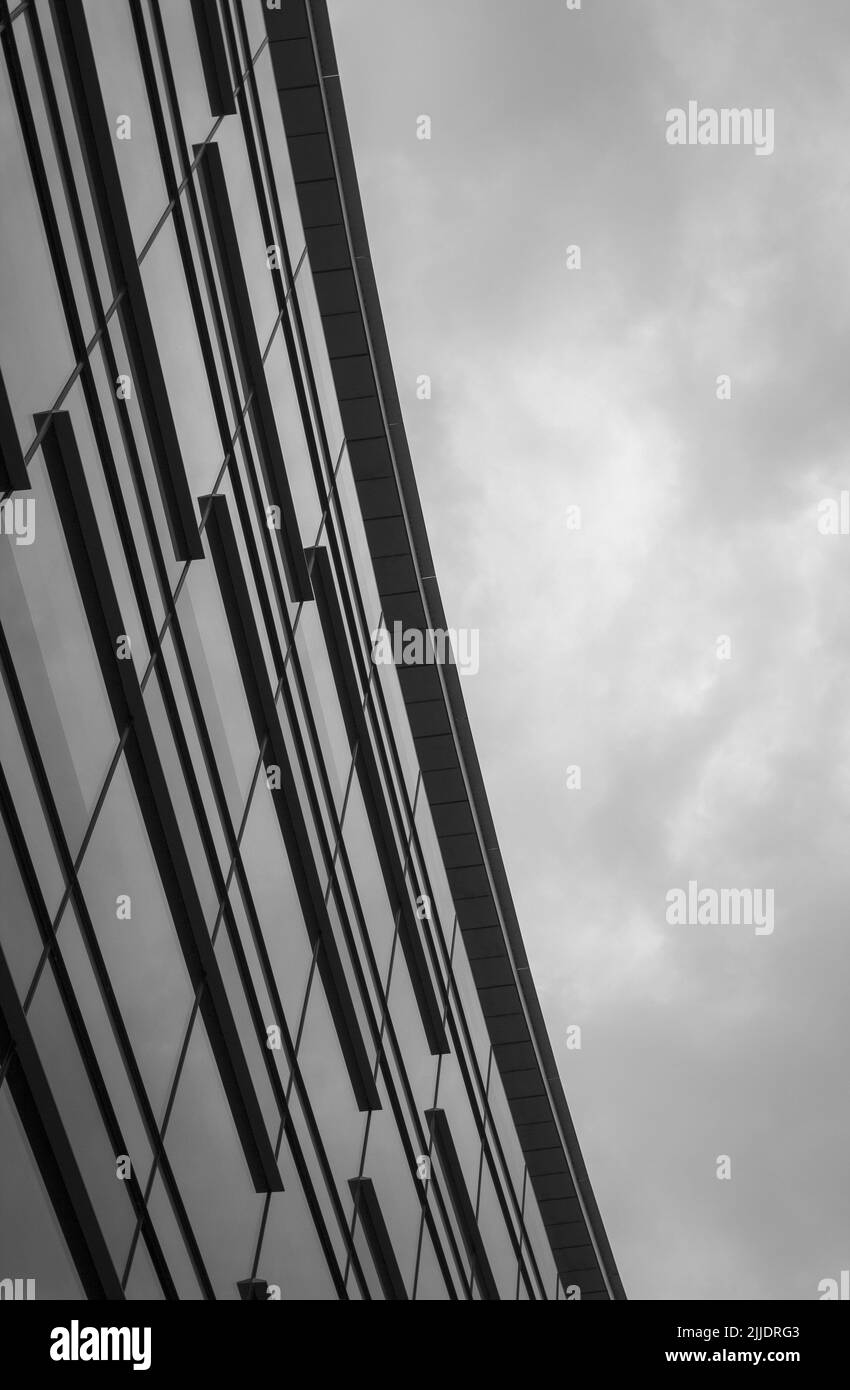 A black and white image of a curved building against a moody sky. Stock Photo