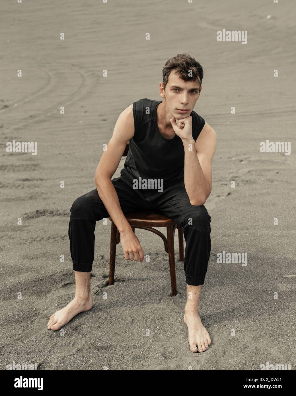 Lone young Man sitting on chair in desert Stock Photo