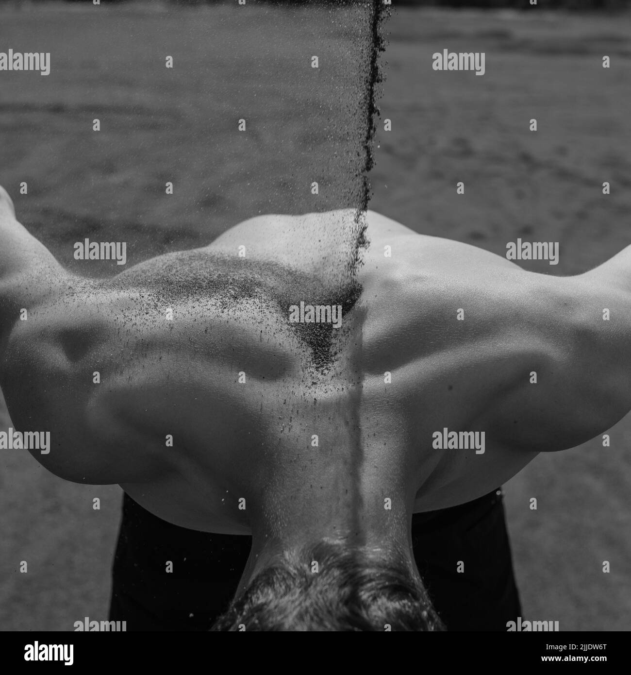 sand falls on the man's back. Black and white Stock Photo