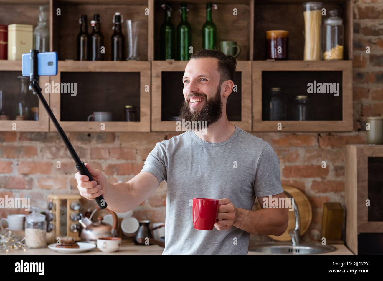 blog video stream man phone selfie stick kitchen Stock Photo