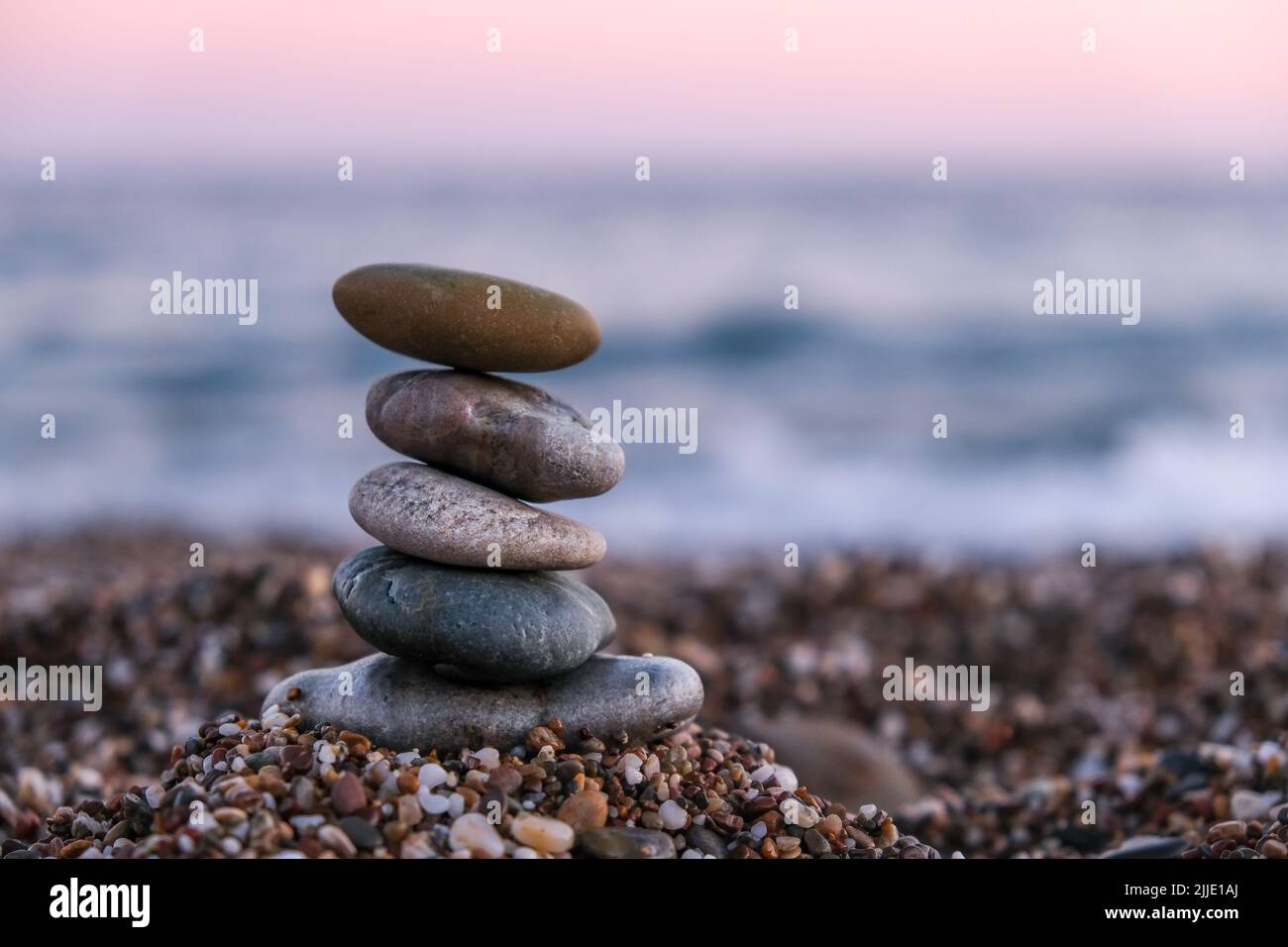 Pyramid of pebbles on the beach at sunset. Concept of zen, stability, harmony, balance and meditation, copy space. Stock Photo