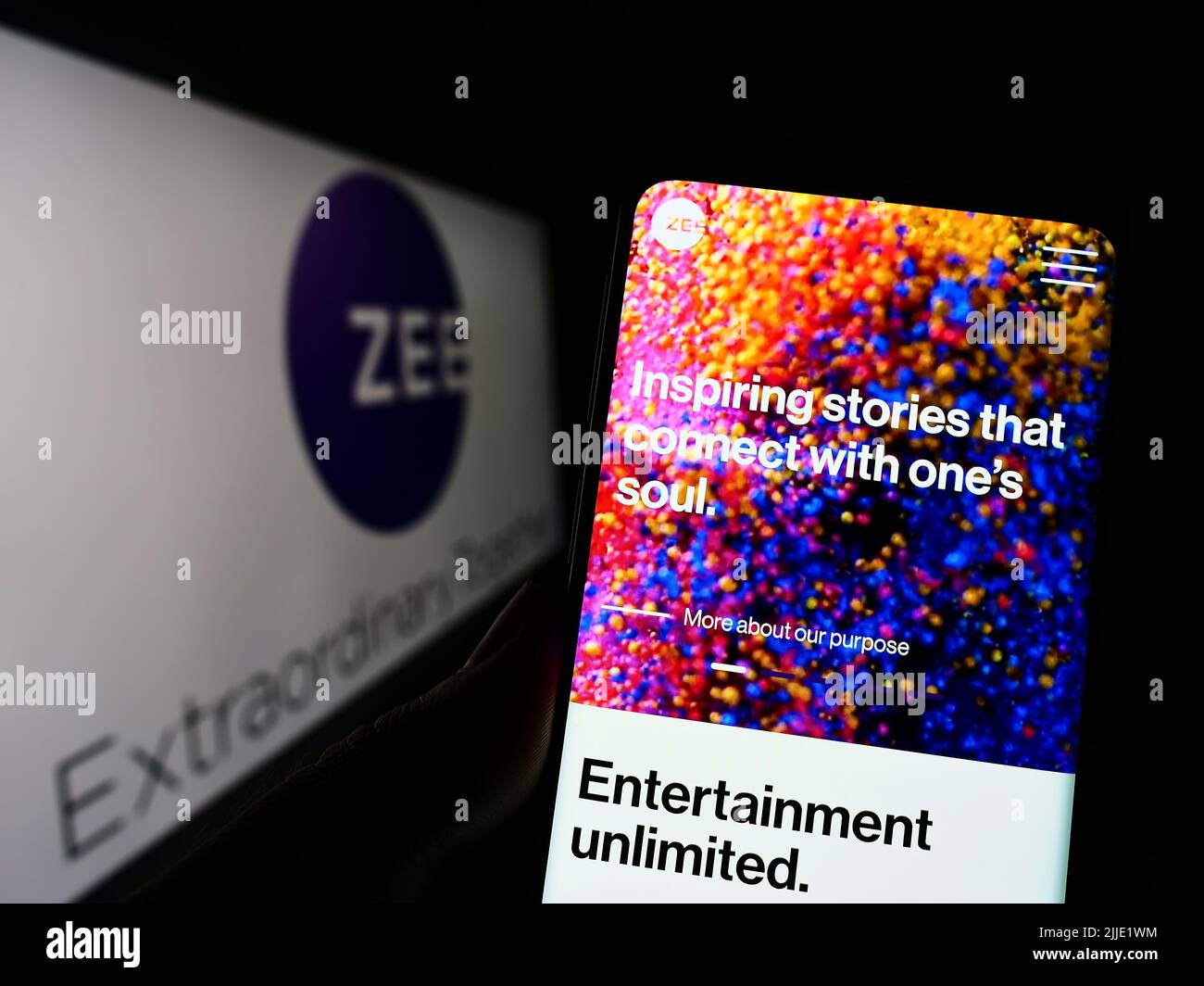 Person holding cellphone with webpage of company Zee Entertainment Enterprises Limited on screen with logo. Focus on center of phone display. Stock Photo
