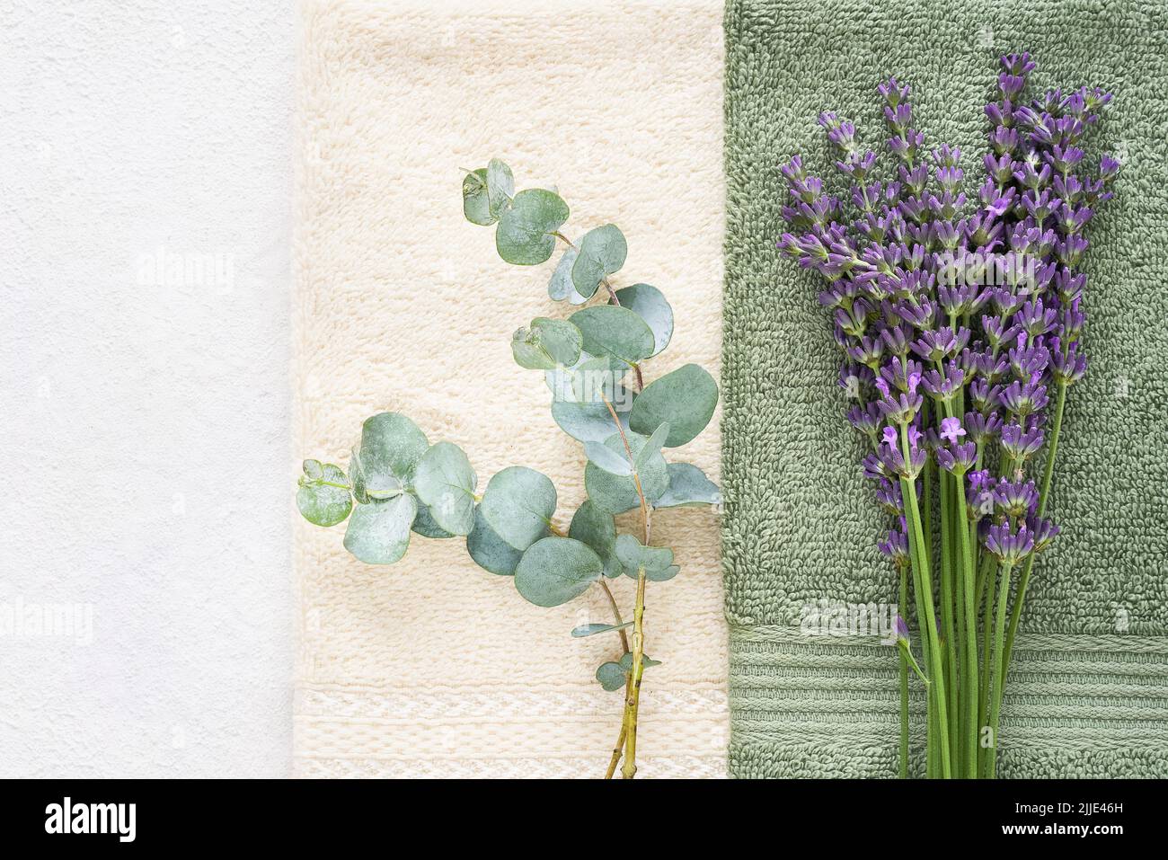 Fluffy towels, green eucalyptus branch and lavender on white background. Minimalist style. Hygiene, wellness well-being, body care concept. Copy space Stock Photo