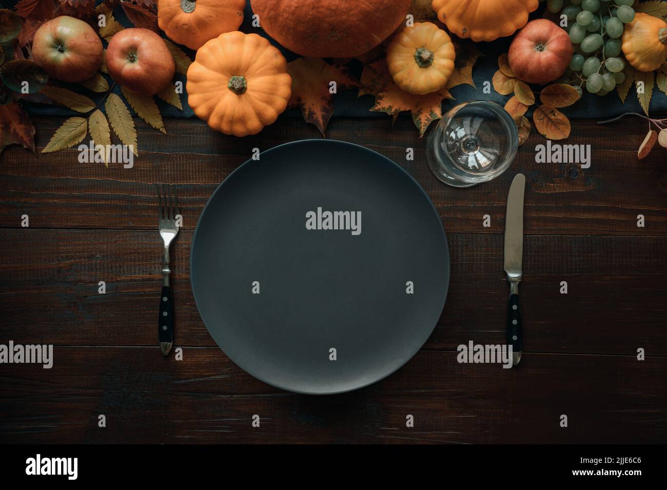 Autumn table place setting with drying leaves and pumpkins. View from ...