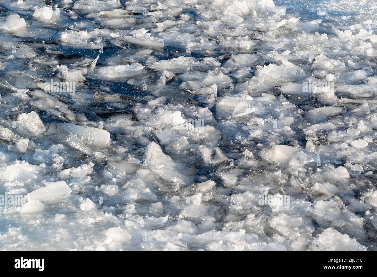 Cracked ice pieces on the frozen water surface in a cold winter day. Stock Photo
