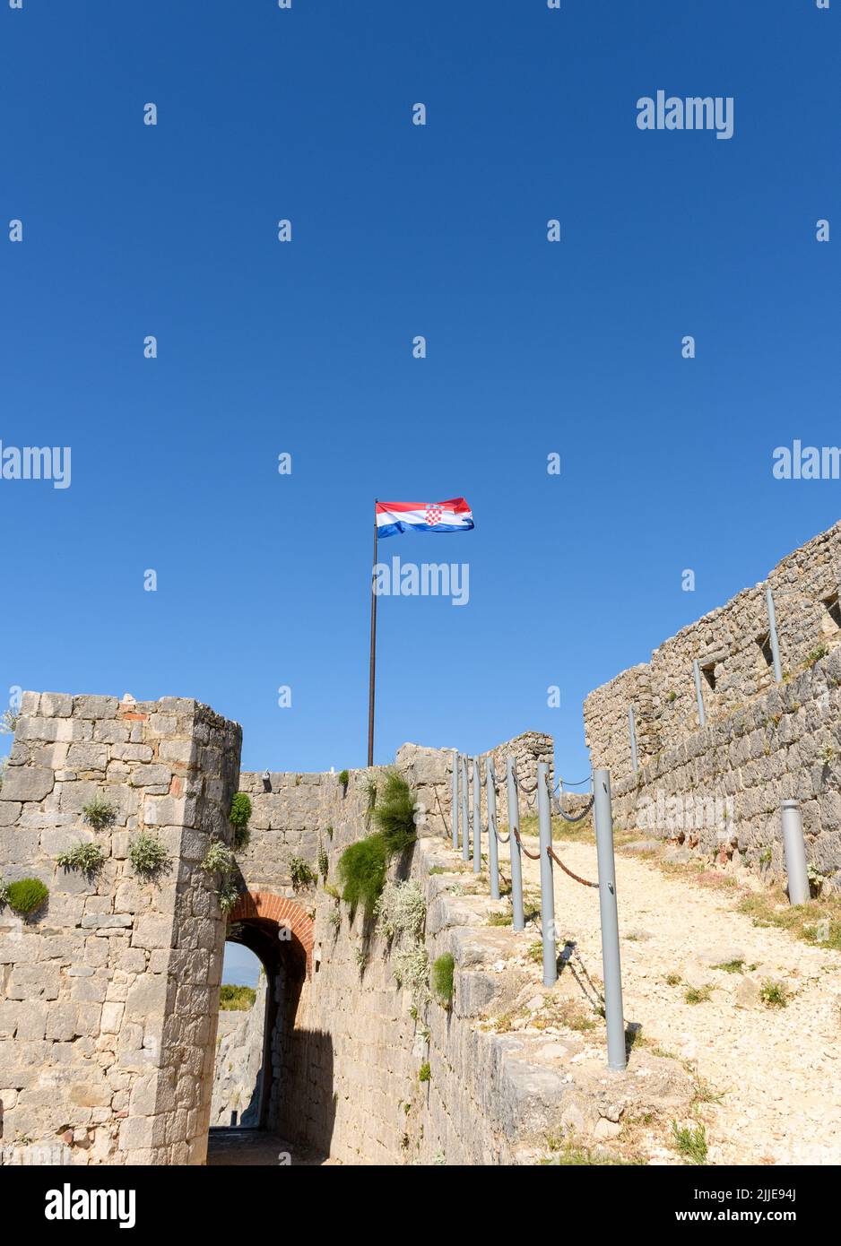 A low angle view of Croatian flag on pole at Klis fortress near the city of Split, Croatia Stock Photo