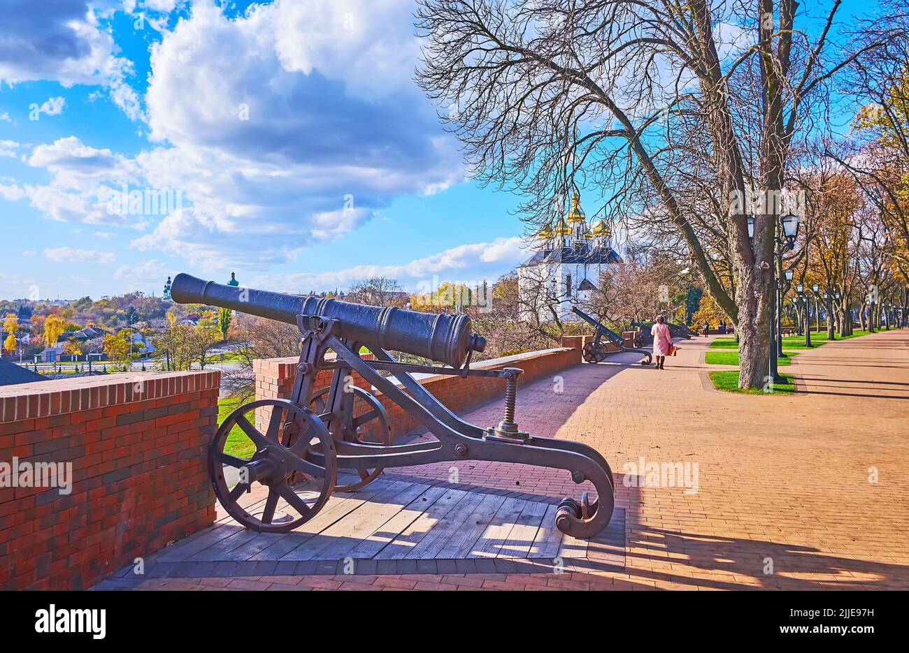 Walk the alley with vintage cannons of Chernihiv Dytynets (Chernigov Citadel) Park with a view on the picturesque golden domed St Catherine's Church, Stock Photo