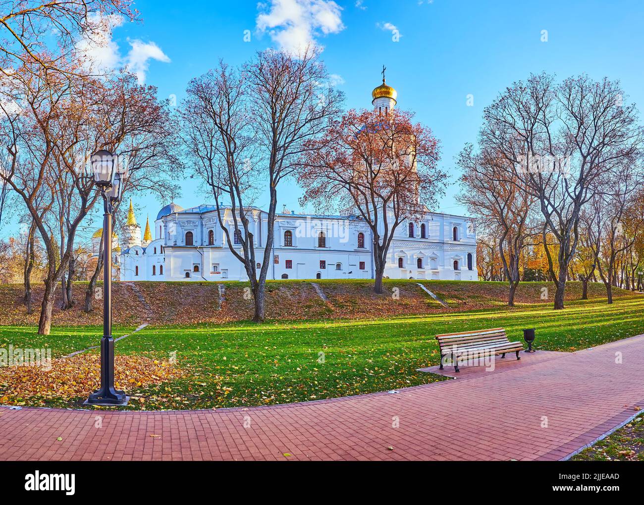 The scenic autumn park of Chernihiv Dytynets citadel with a view of Chernihiv Collegium behind the lawn and the rampart hill, Chernihiv, Ukraine Stock Photo