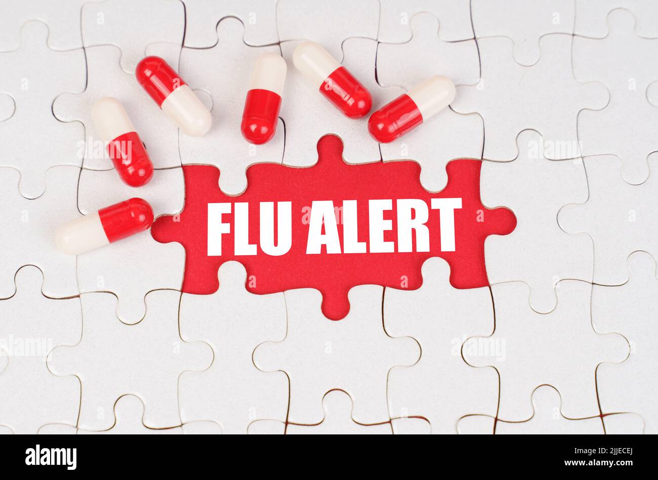Medical concept. There are pills on the white puzzles, in the middle there is a red surface with the inscription - Flu alert Stock Photo