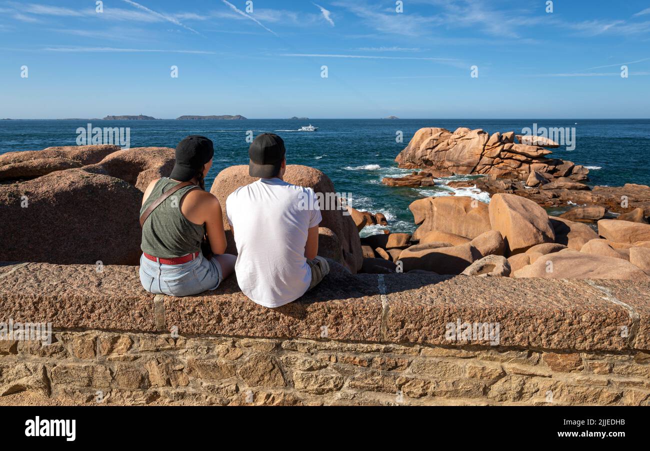 Young couple in love watching a beautiful seascape from the Ploumanac'h lighthouse at sunset. Stock Photo
