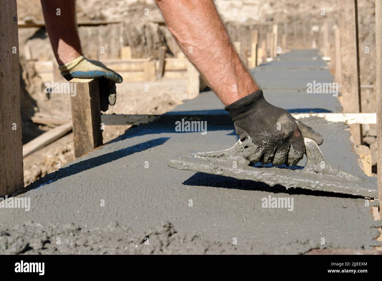 Construction worker spreading concrete mix of house foundation Stock Photo