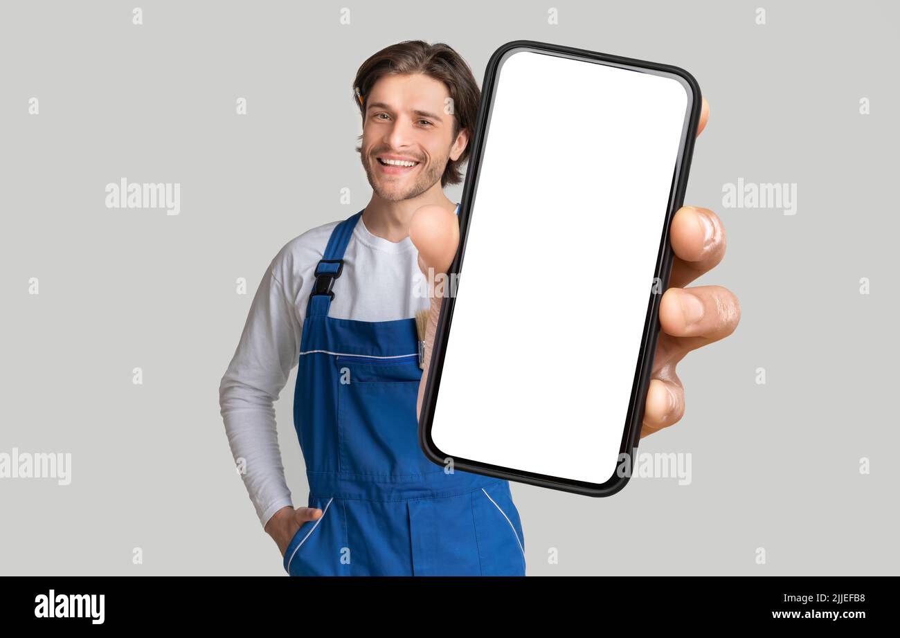 Young Handyman Showing Mobile Phone With Blank Screen Stock Photo
