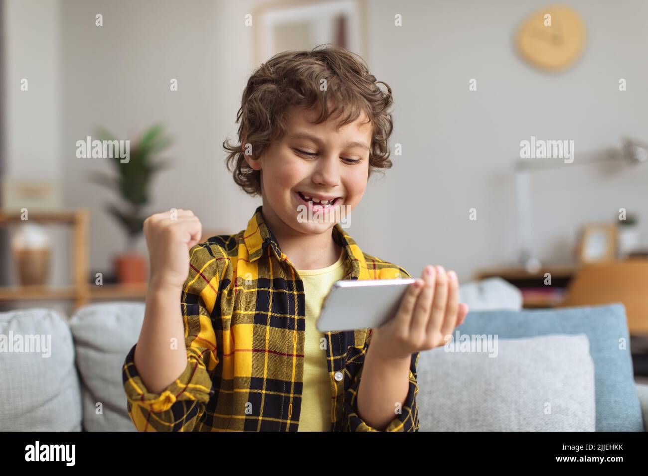 Online win. Happy little boy watching game on phone, celebrating victory,  enjoying streaming at home, free space Stock Photo - Alamy