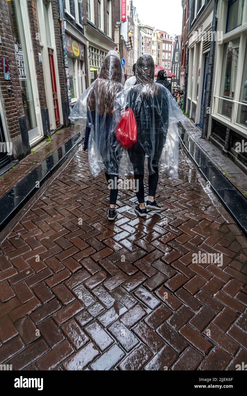 Tourists in rainy weather, wearing plastic ponchos, in the old town of Amsterdam, Netherlands. Stock Photo