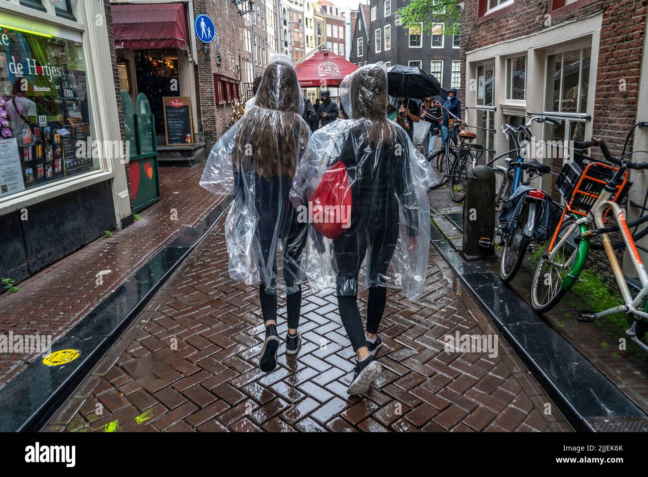 Tourists in rainy weather, wearing plastic ponchos, in the old town of Amsterdam, Netherlands. Stock Photo