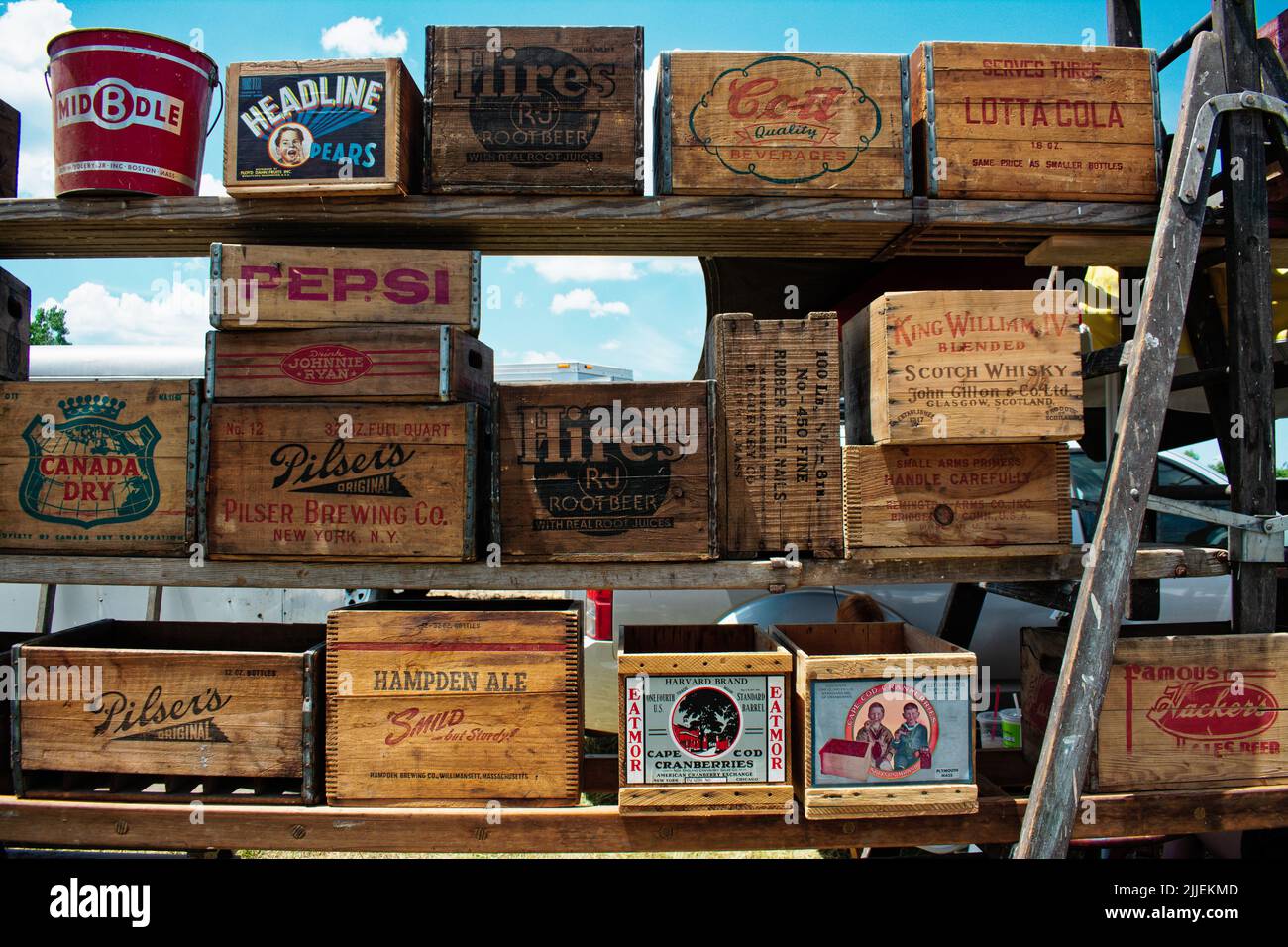 A display of vintage wooden crates on shelves at an outdoor flee market