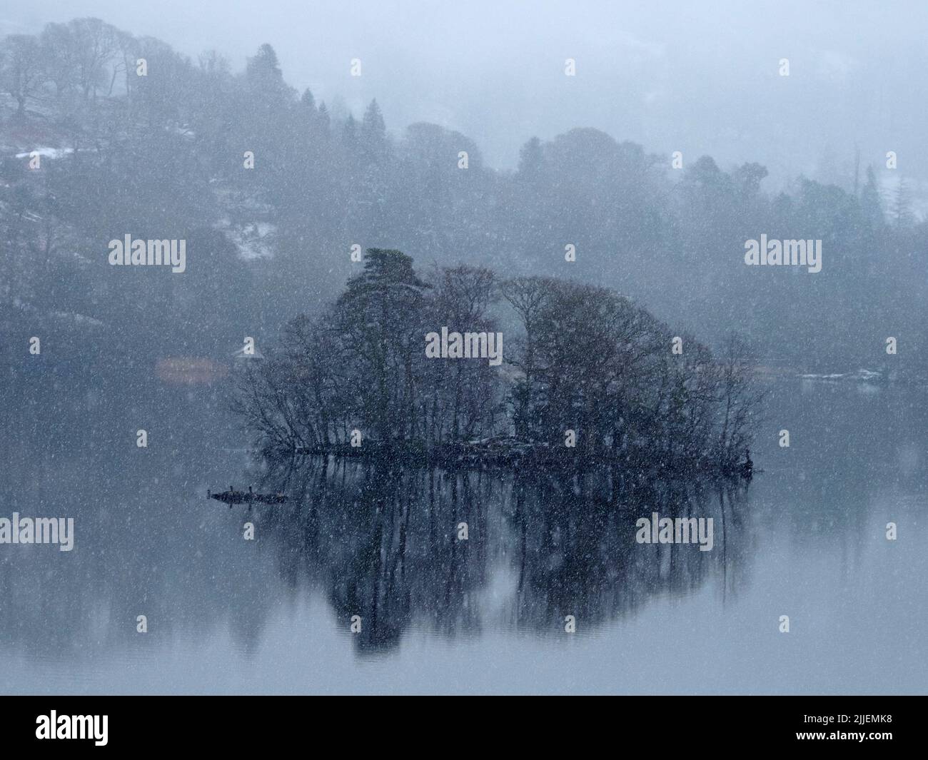 snow falling over bare trees reflected in still wintry waters of Rydal Water near Grasmere,Cumbria,England, UK Stock Photo