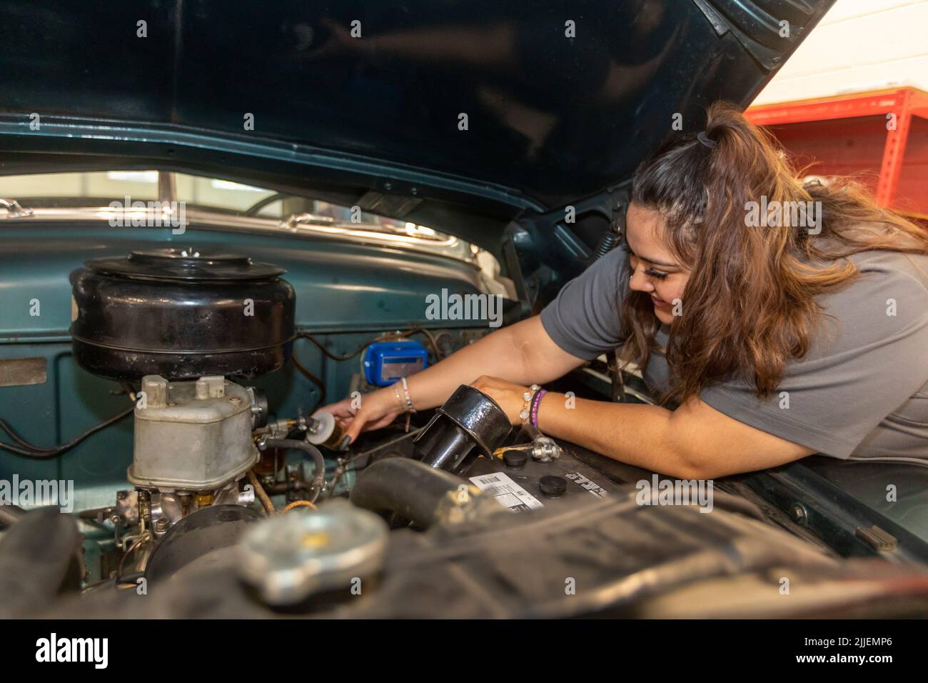 Aurora, Colorado - Cinthia Cabral replaces a car's fuel filter at Hands of the Carpenter. The nonprofit repairs vehicles belonging to single mothers a Stock Photo
