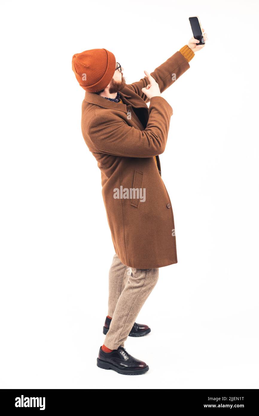 Full body shot of an stylish man in a coat taking selfie - isolated on white background. High quality photo Stock Photo