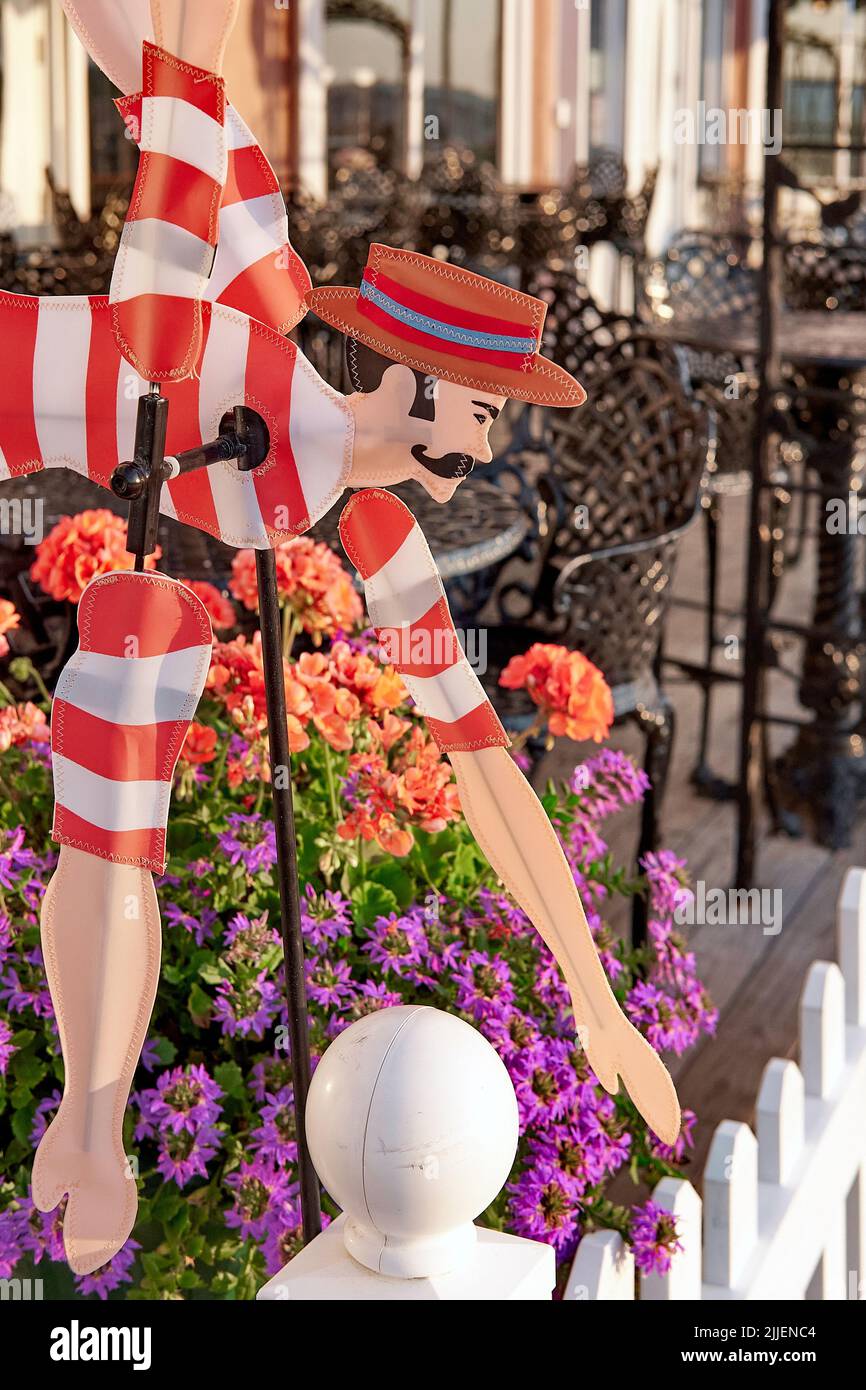 A colorful whirligig depicting a male Victorian era swimmer brightens a seaside themed garden and patio. Stock Photo