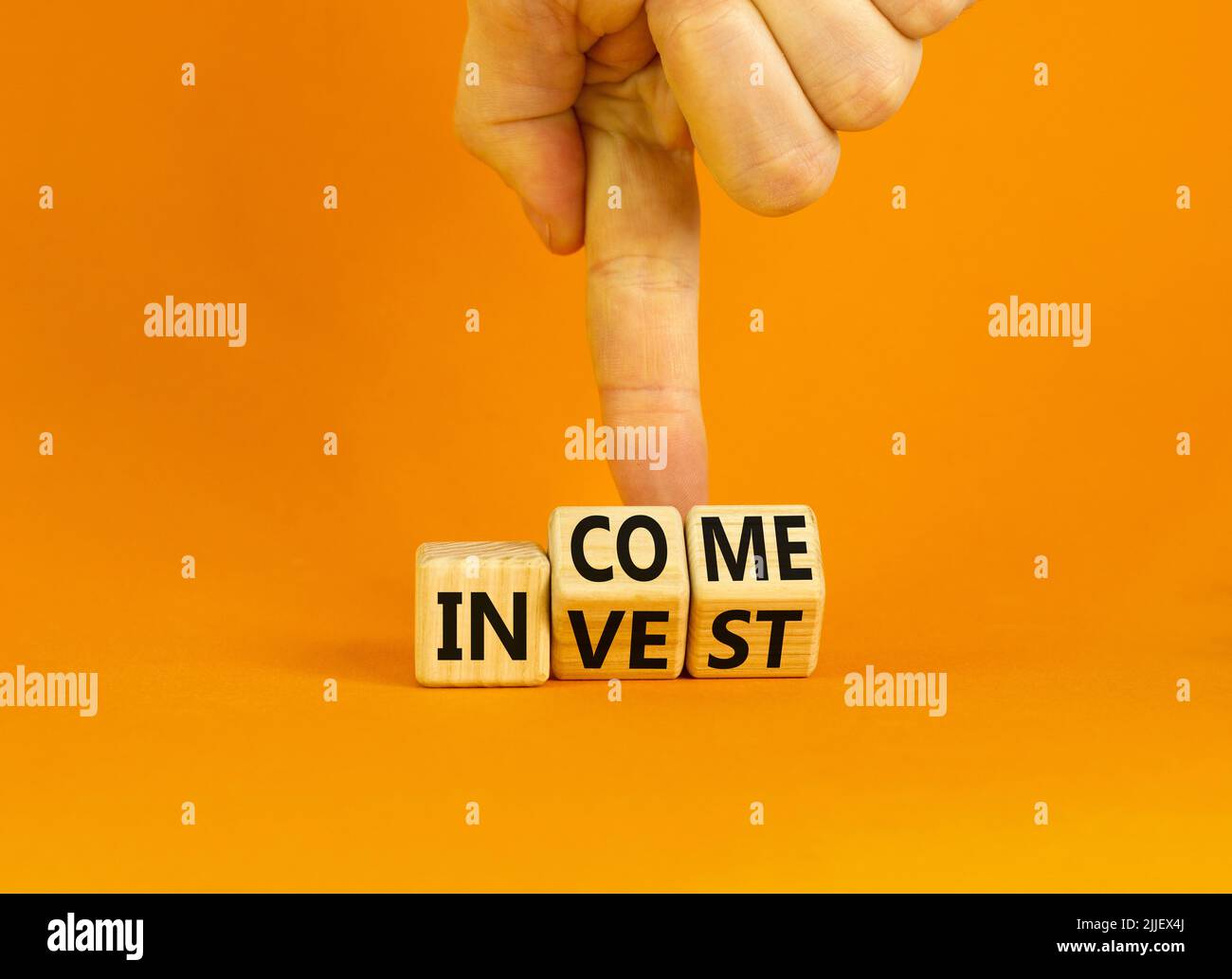 Invest or income symbol. Concept words Invest and Income on wooden cubes. Businessman hand. Beautiful orange table orange background. Business and inv Stock Photo