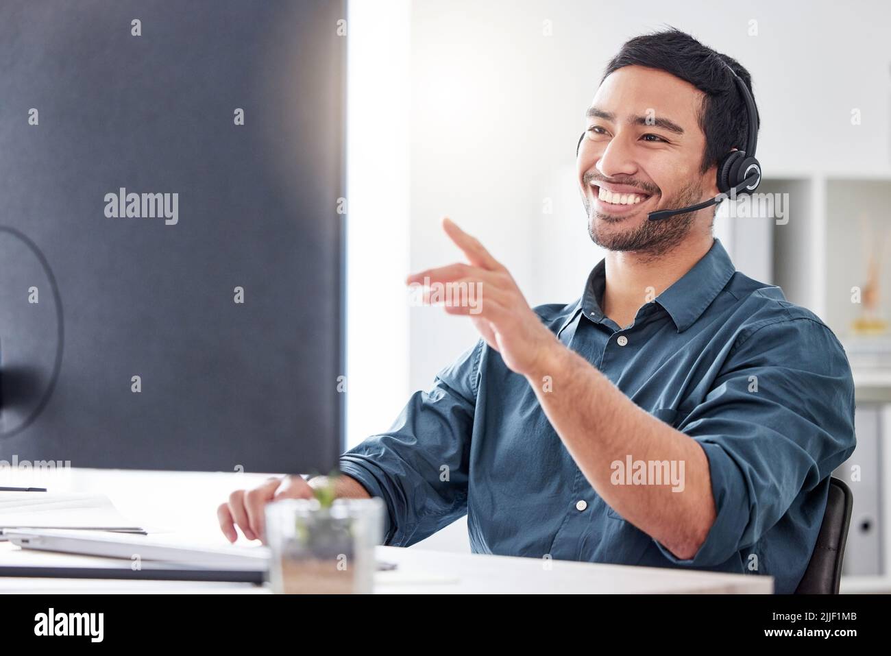Lemme just pull up your details. a handsome young male call center agent working in his office. Stock Photo