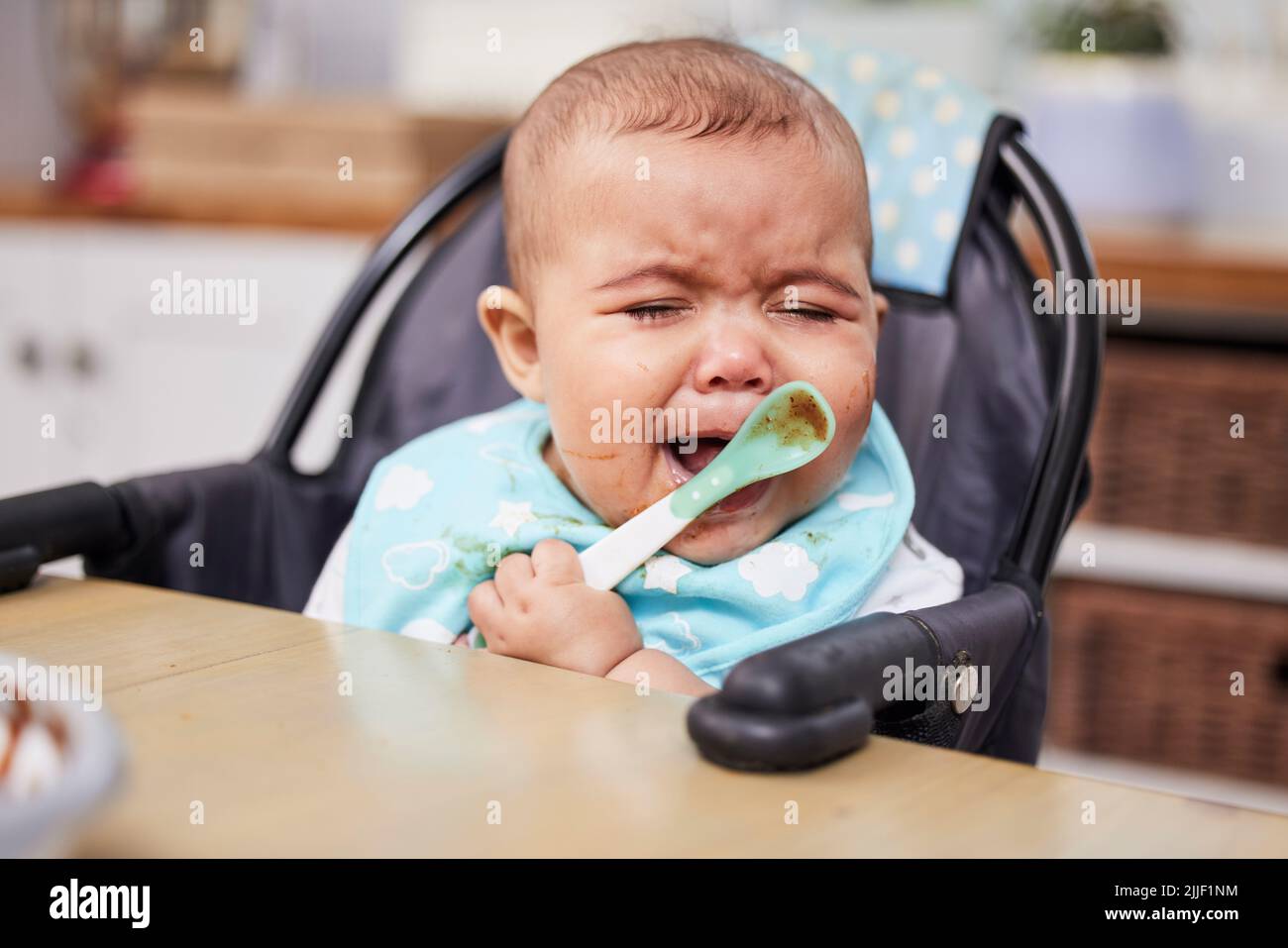Why do I love food this much. a baby crying while eating a meal Stock