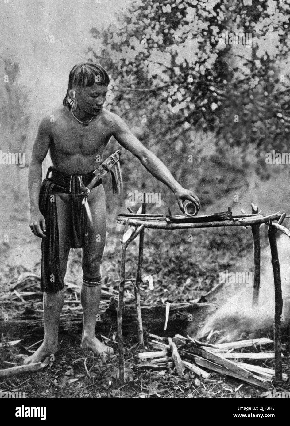A Dayak man from Bornoe mixing the poison for his dart blowpipe, probably from the sap of Antiaris toxicaria and Styrchnos nux-vomica; Image published 1929. Stock Photo