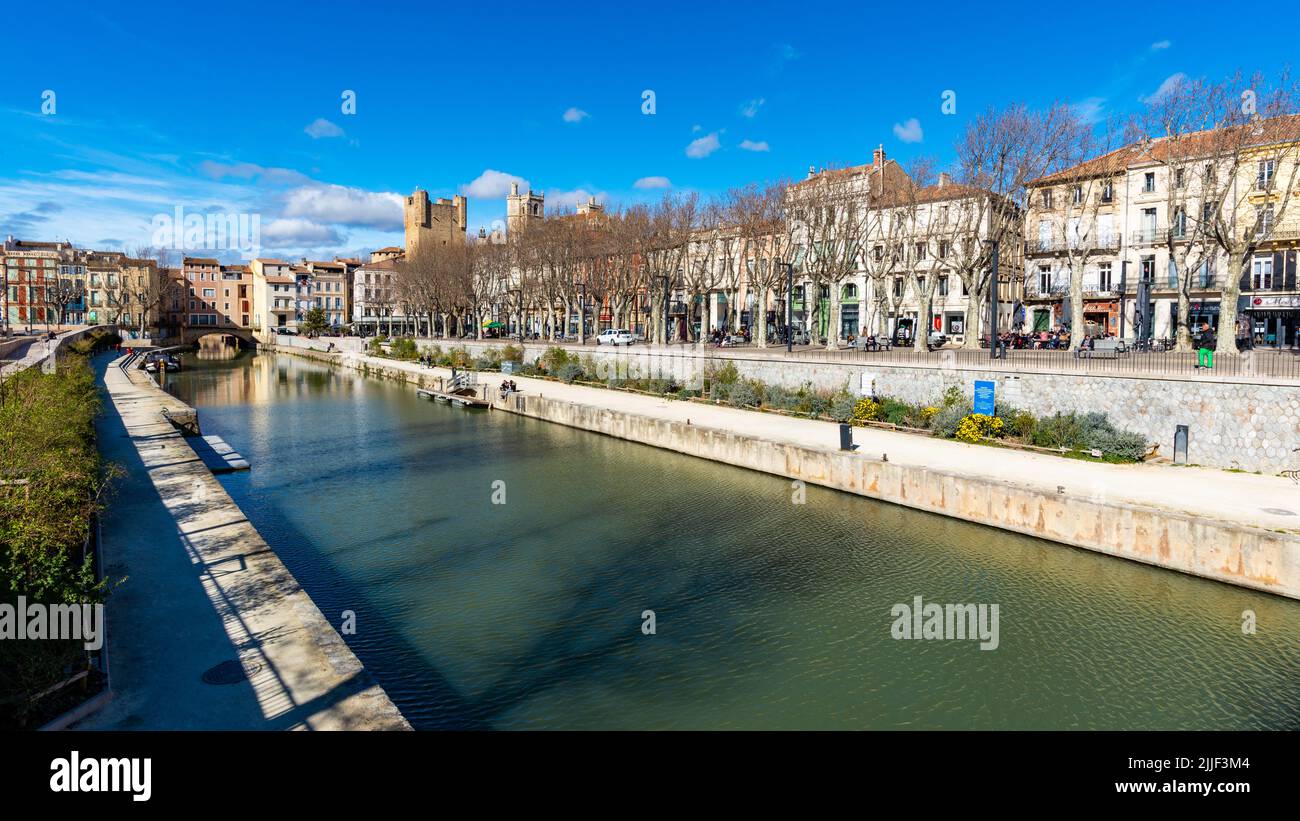 Narbonne, France - February 20, 2022: Canal de la Robine in the old city of Narbonne, taken on a sunny winter afternoon, with some people far in the b Stock Photo