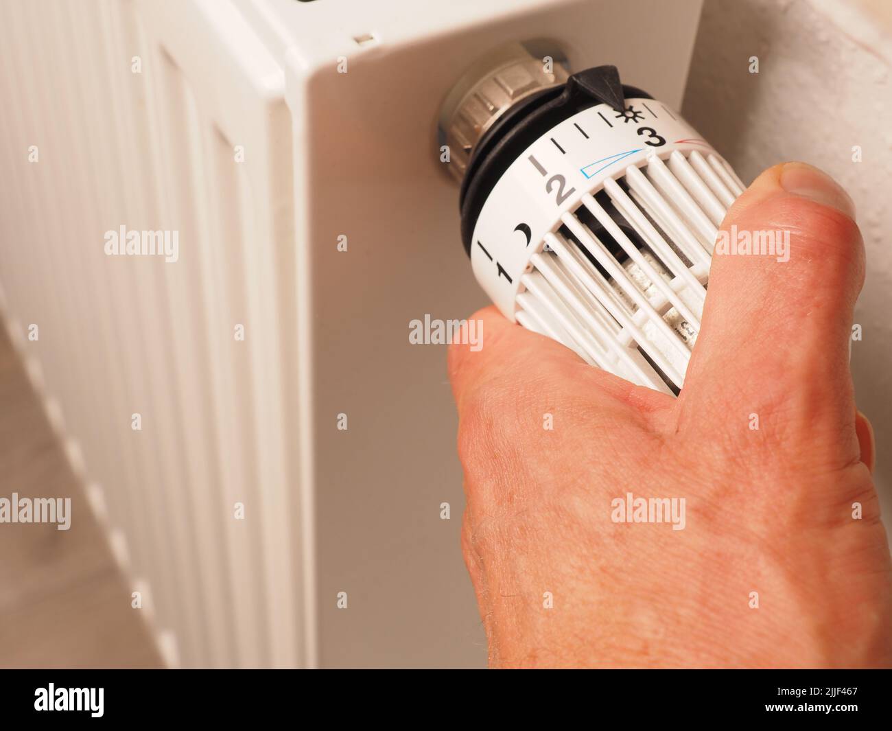 Hand turns the thermostat of a radiator, save energy, reduce energy